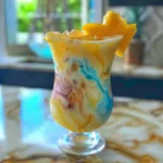 Ocean Love Colada recipe mocktail in a hurricane glass with pineapple and mint